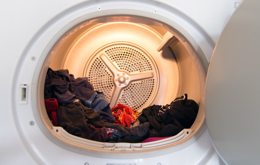 Open dryer with clothes inside, highlighting FixEmApplianceRepair services in Oakland.